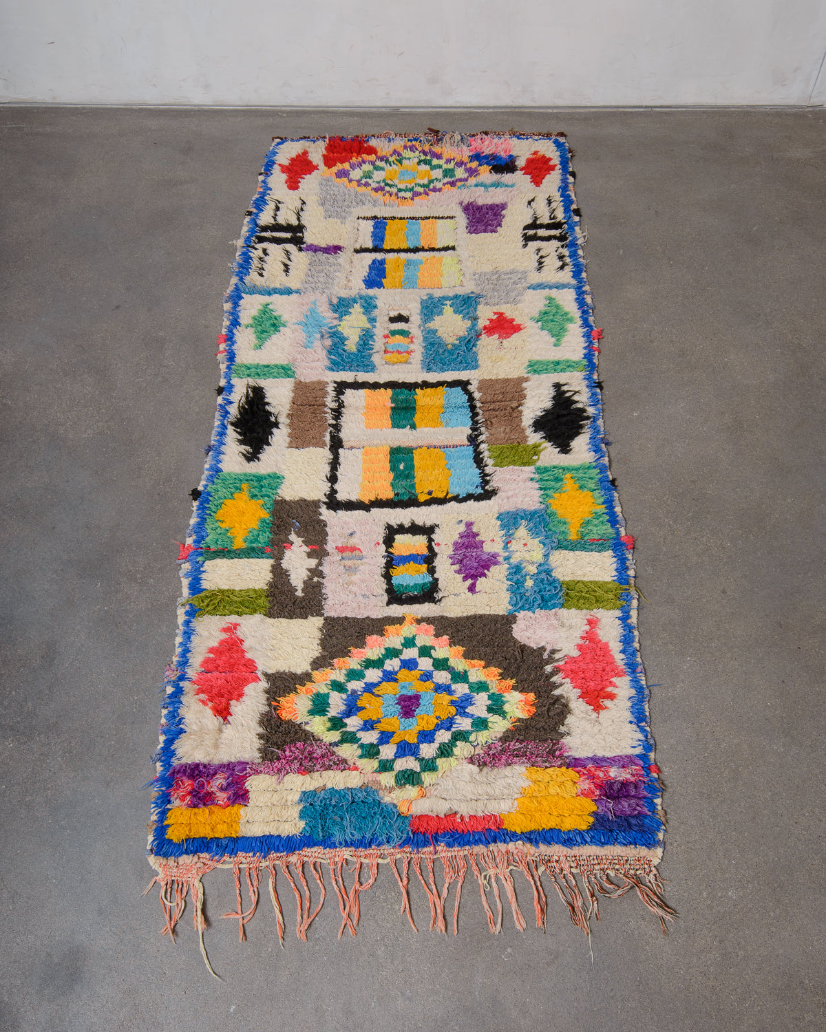 Colourful Boucherouite runner rug laying on concrete studio floor.